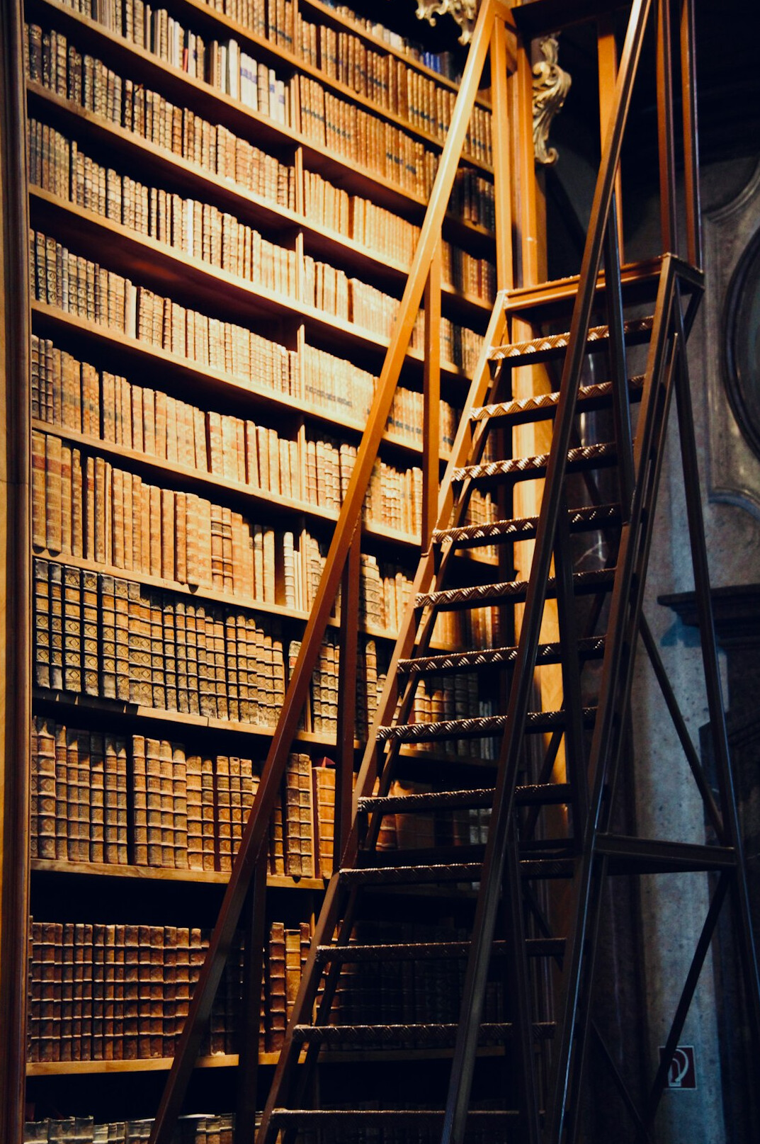 Old library archive with tall bookshelves and a wooden ladder