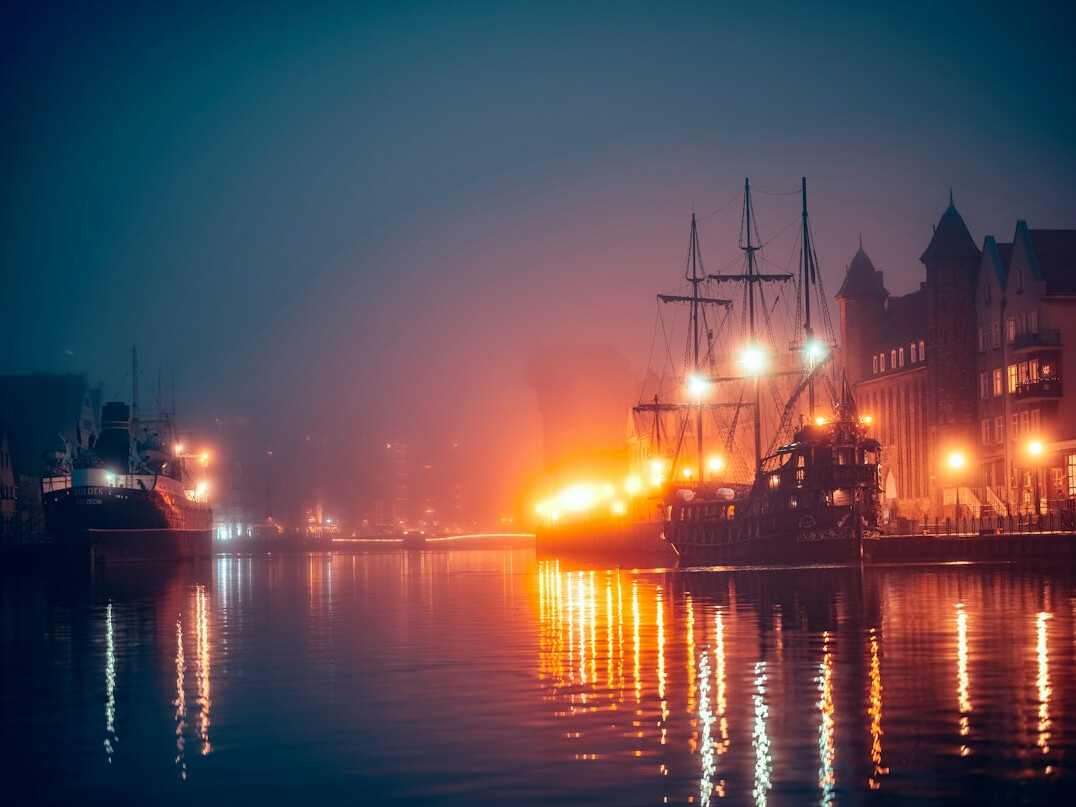 Foggy harbor at night with old fishing boats and lanterns