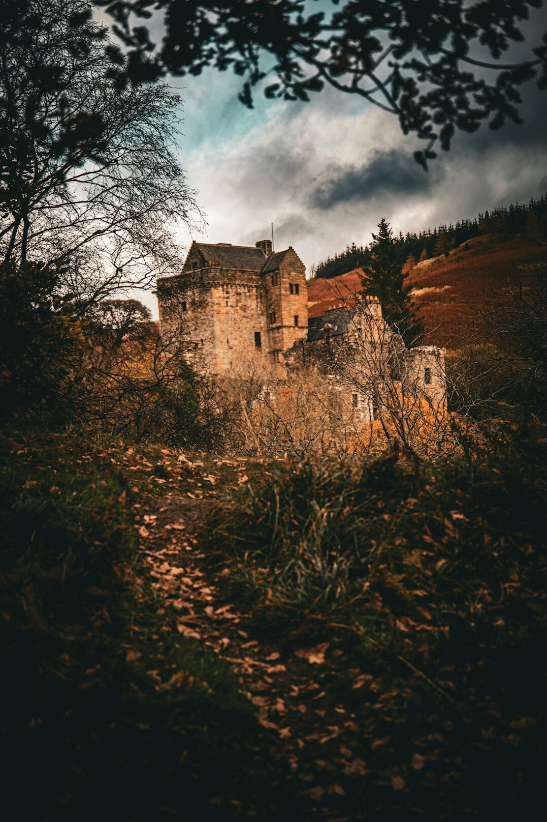 Moody photo of an old stone house on a hill under a stormy sky